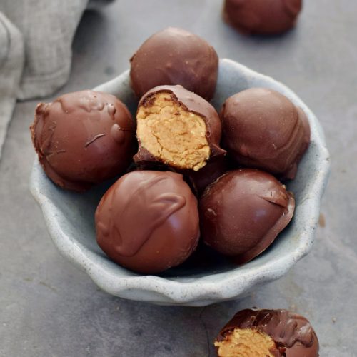 peanut butter truffles in ceramic bowl with one cut open 500x500